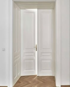 an empty room with two white doors leading to another room that has wood floors and parquet flooring