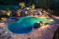 an aerial view of a swimming pool at night with lights on the side and water slide in the middle