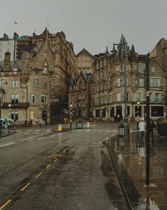 people are walking on the street in front of some old buildings with rain pouring down