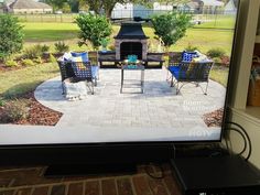 a flat screen tv sitting on top of a brick patio next to a fire place