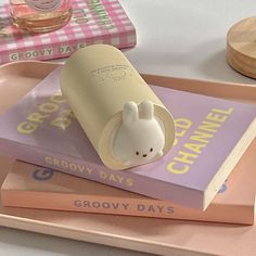 there is a small toy rabbit on top of some books in the shape of a coffee cup