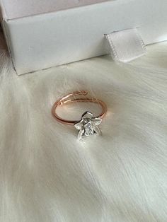 a diamond ring sitting on top of a white fur covered floor next to a box