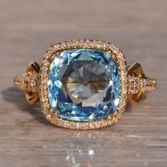 a fancy ring with an aqua blue stone surrounded by gold and diamond trimmings