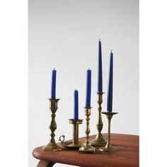 three brass candlesticks on a wooden table with one blue candle in the middle