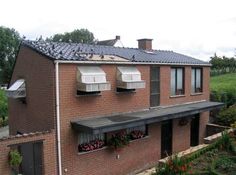 a brick house with windows and shutters on the roof