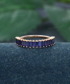 a gold ring with blue sapphire stones on the inside and outside, sitting on top of a black surface