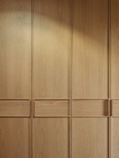 an empty room with wood paneling on the walls and cupboards in front of it