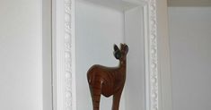 a wooden horse is standing in the corner of a door handle on a white wall