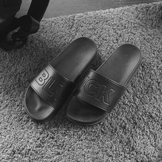 a pair of black slippers sitting on top of a rug