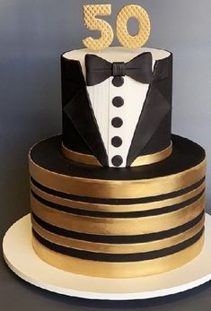 a black and gold 50th birthday cake with a tuxedo on top