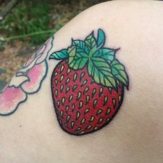 a close up of a person's shoulder with a strawberry tattoo on it