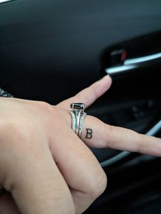 a woman's hand with a ring on top of her finger in a car