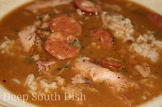 a bowl of soup with shrimp, rice and garnish on the side is ready to be eaten