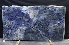 a large blue marble slab sitting on top of a metal stand in front of a black backdrop