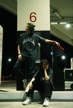 two people sitting on the ground with one holding a skateboard in front of them