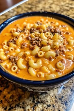 a blue bowl filled with macaroni and cheese soup on top of a counter