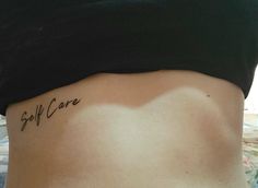 a woman's stomach with the word self care tattooed on her lower back side