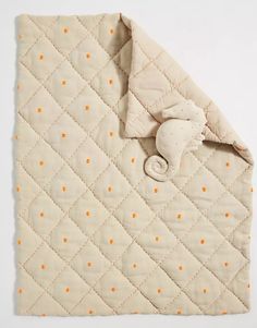 an orange and white quilted blanket with polka dots on it, next to a stuffed animal