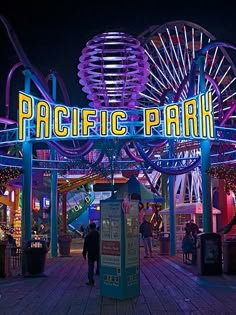 people are walking around an amusement park at night