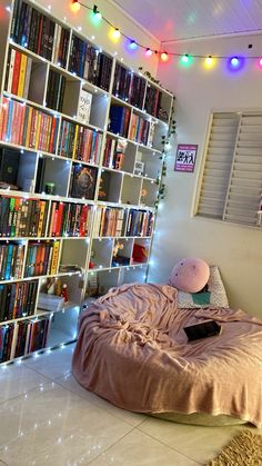 a bedroom with bookshelves and lights on the ceiling, along with a bed covered in a pink comforter