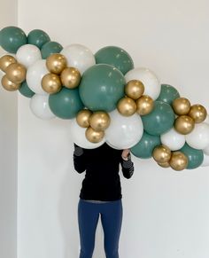 a woman is holding balloons in the shape of a wave with gold and white balls