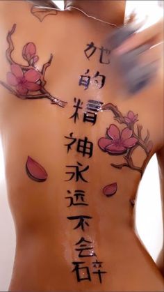 the back of a woman's body with chinese writing and flowers painted on it