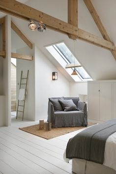 an attic bedroom with white floors and wooden beams