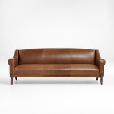 a brown leather couch sitting on top of a white floor next to a wooden frame