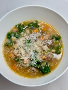 a bowl of soup with meat, vegetables and parmesan cheese on the side