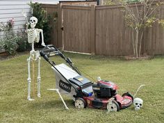 a lawn mower sitting in the grass next to a skeleton