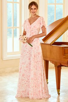 a woman standing in front of a grand piano wearing a pink dress with floral print