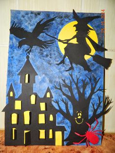 a paper cut out of a halloween scene with a spider and witch on the roof