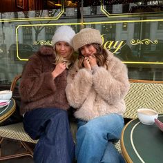 two women sitting next to each other in front of a window