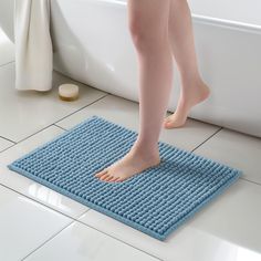 a person standing on a blue mat in front of a bathtub