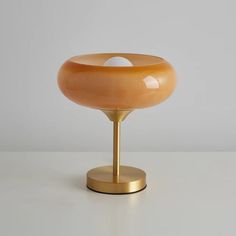 a table lamp with an orange glass bowl on it's base and two white balls in the center