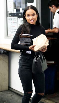 a woman in black holding a brown paper bag