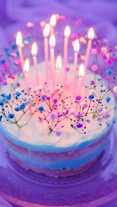 a cake with white frosting and lit candles on it sitting on a purple plate