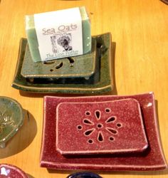 four ceramic dishes on a wooden table with labels in the middle one is green and the other two are red