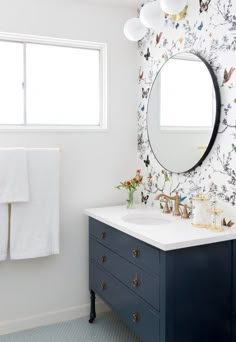 a bathroom with a sink, mirror and wallpaper on the walls is shown in this image