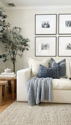 a living room with white couches and pictures on the wall above them, along with a coffee table