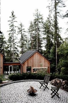 two lawn chairs sitting on top of a stone patio next to a fire pit in the middle of a forest