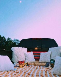 a truck with pillows and blankets on the bed in front of it is parked next to a picnic table