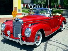 an old red car is parked on the street