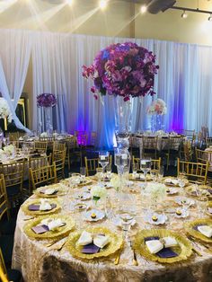 a banquet room set up with gold and purple tablecloths, silverware, and centerpieces