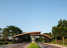 an empty street with a large arch in the middle and grass on both sides, surrounded by trees