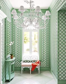 a white bench sitting under a chandelier next to a window in a green room