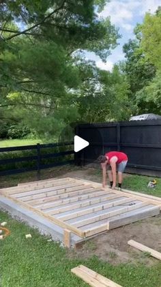 two people are working on building a house in the yard with wooden boards and pallets