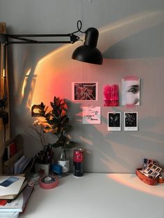 a desk with some books and pictures on the wall next to a potted plant