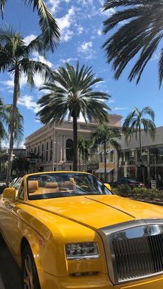 a yellow car is parked on the side of the road in front of palm trees