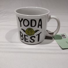 a white coffee mug with yoda best on it next to a green credit card